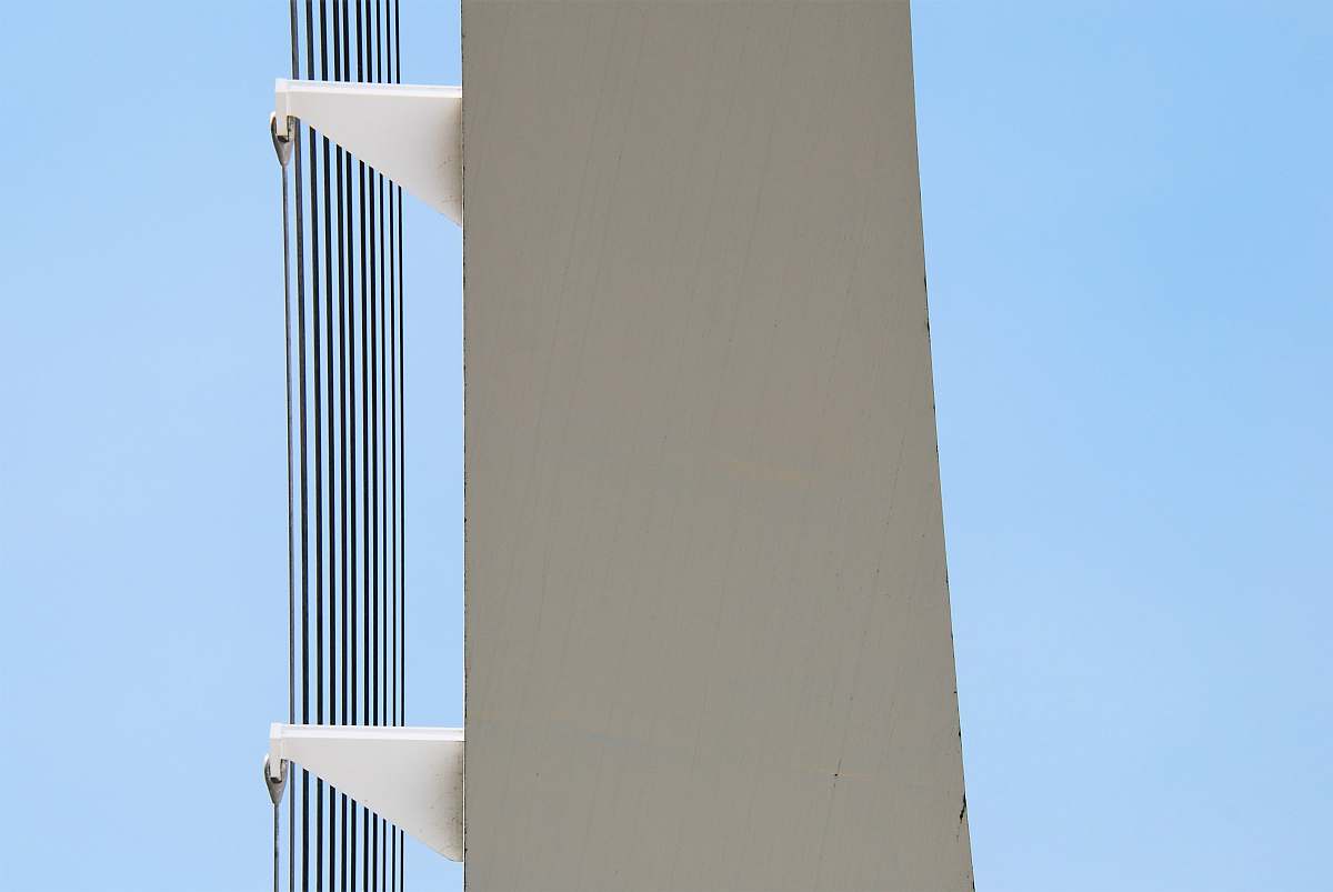 This captivating image features a tall, pristine white building, elegantly rising against a backdrop of clear blue sky. The contrast of the building's smooth lines with the vibrant sky creates a striking visual effect suitable for various uses, such as architectural presentations, travel blogs, or real estate listings. Perfect for capturing the essence of urban beauty and modern design.
